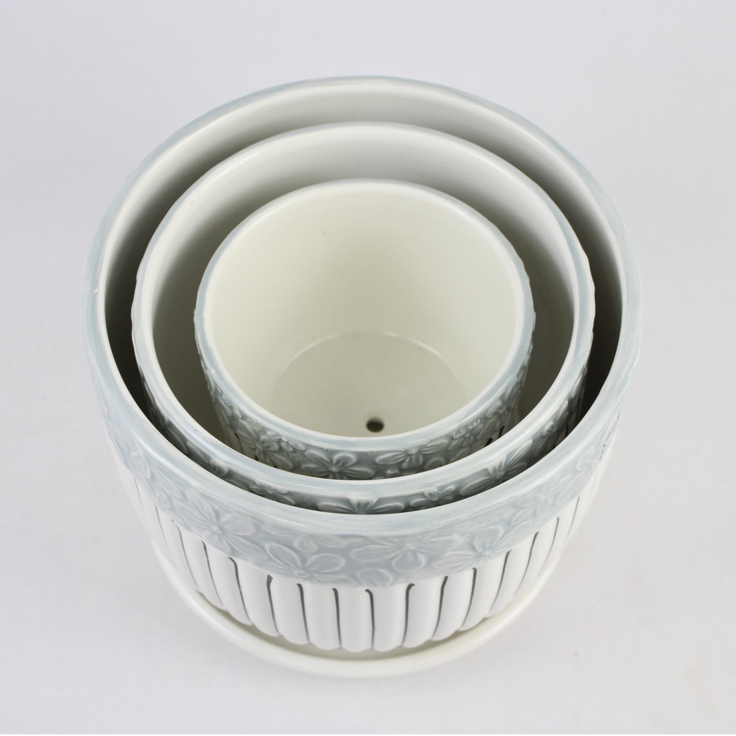 Set of three white ceramic bowls with floral patterns on a light gray background