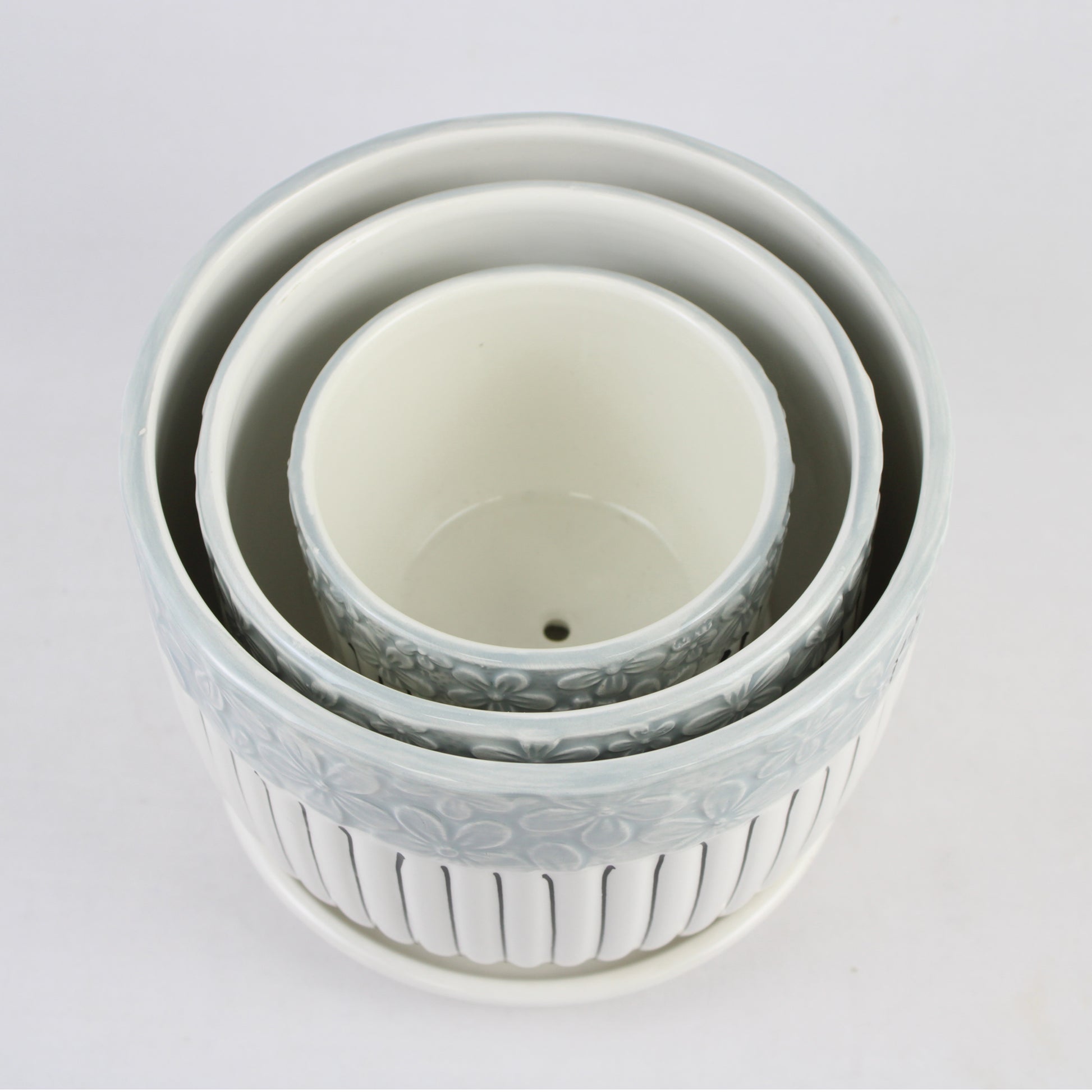 Set of three white ceramic bowls with floral patterns on a light gray background