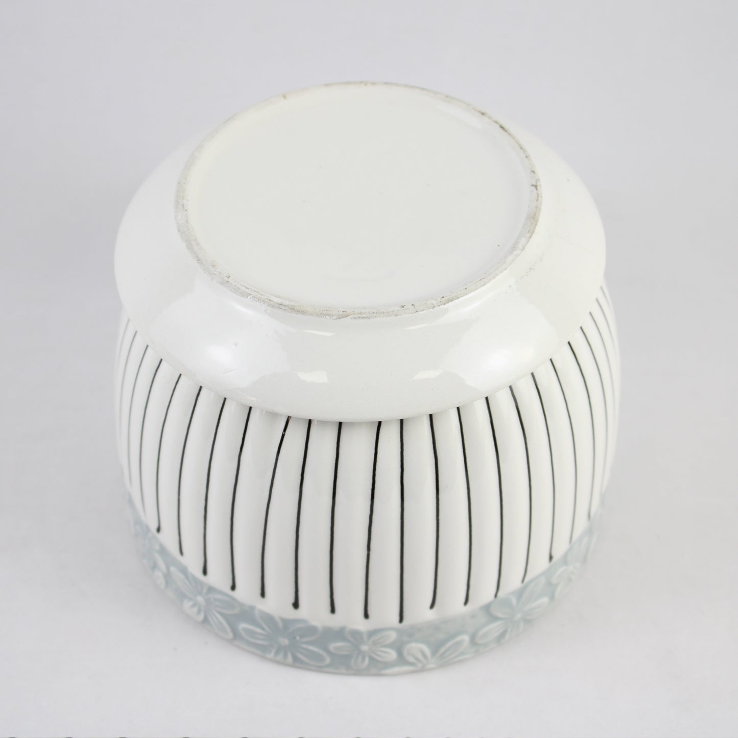 White ceramic jar with black vertical stripes on a light gray background