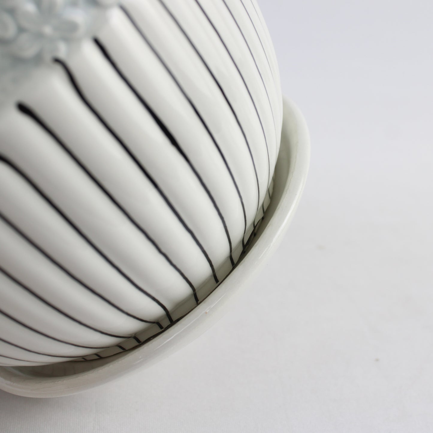 Close-up of a white ceramic bowl with black lines on a light gray background